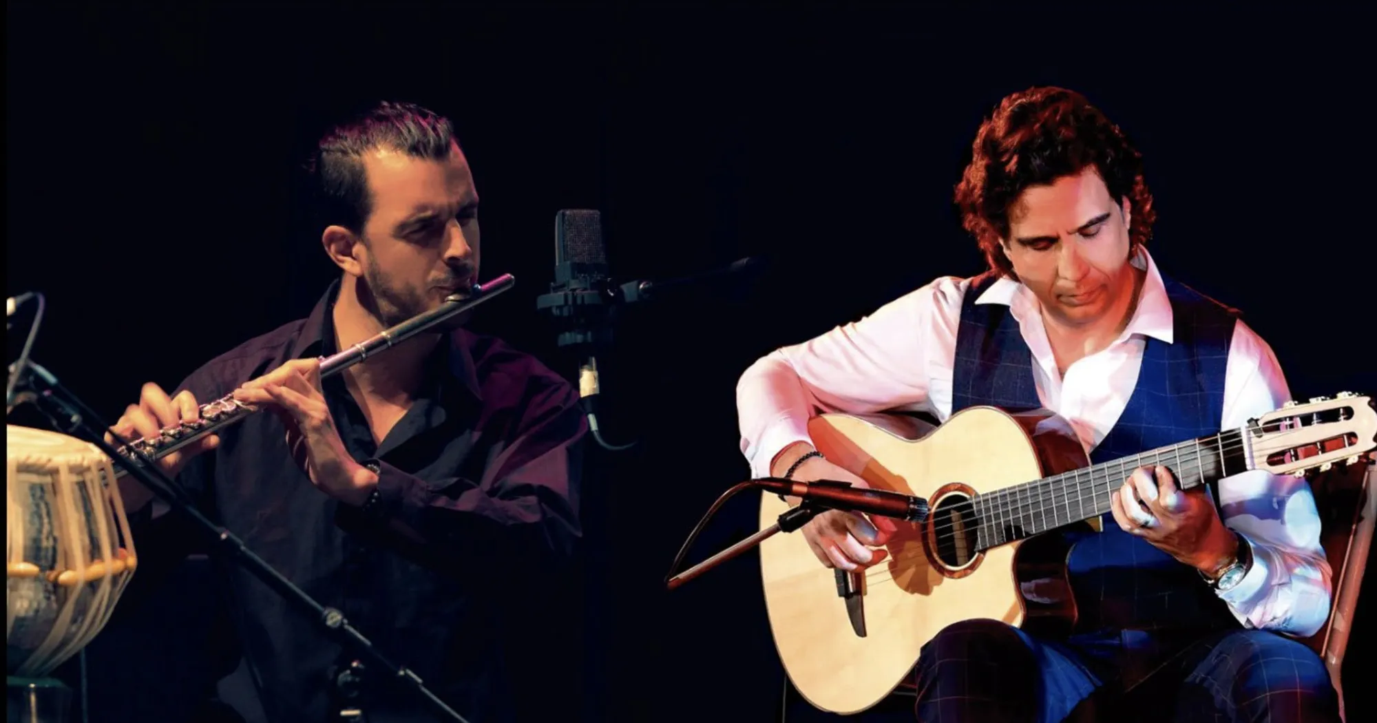Rodrigo Parejo on flute and Ernesto Castillo on guitar, performing on a dark stage